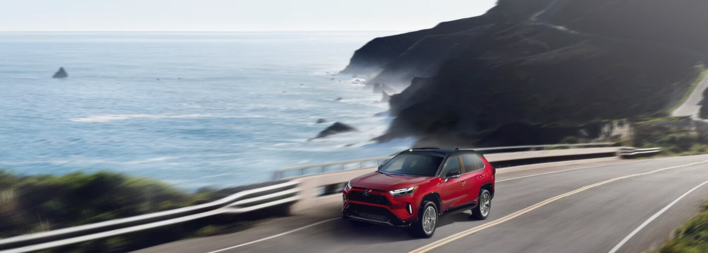 2026 Red Toyota RAV4 Hybrid driving on the coast 