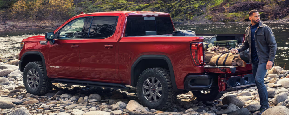The red truck is parked on a riverbank. 