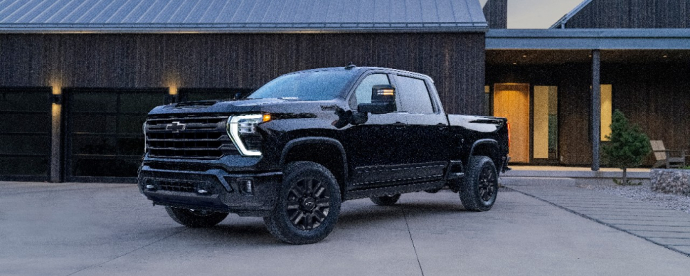 2024 Chevy Silverado 2500 HD A black Chevy Silverado 2500HD is parked in front of a garage.