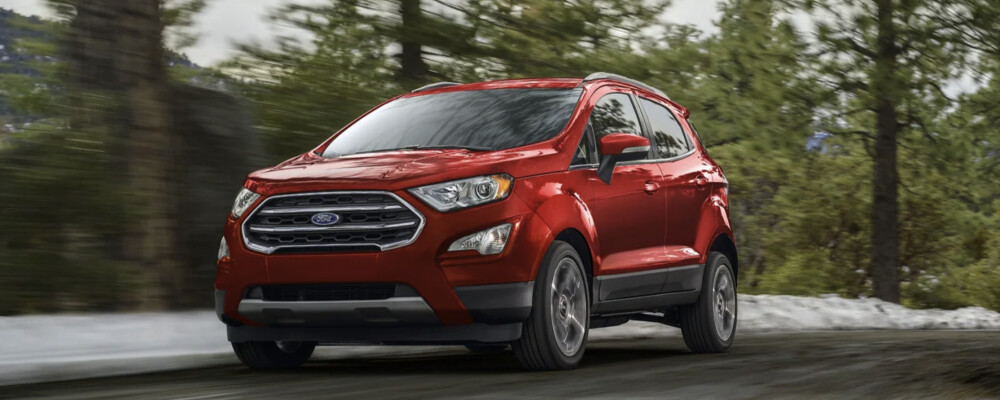 Red 2022 Ford EcoSport driving near woods Red 2022 Ford EcoSport driving near woods