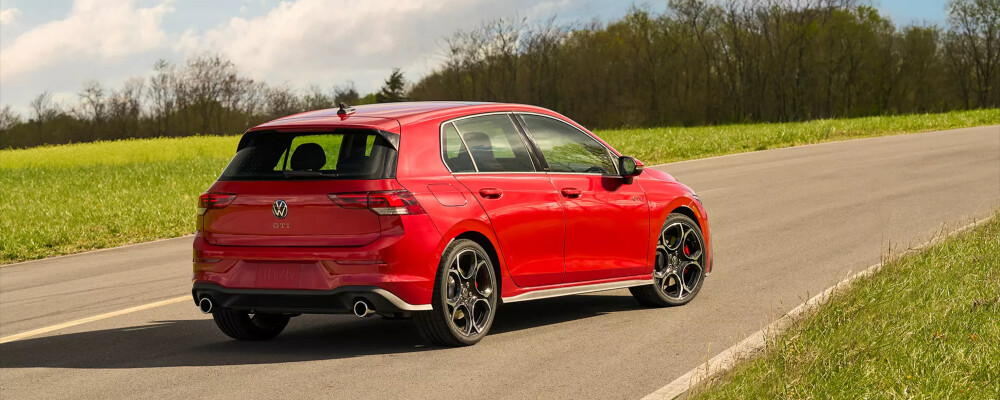 Red 2026 Volkswagen Golf GTI traveling on road towards nature