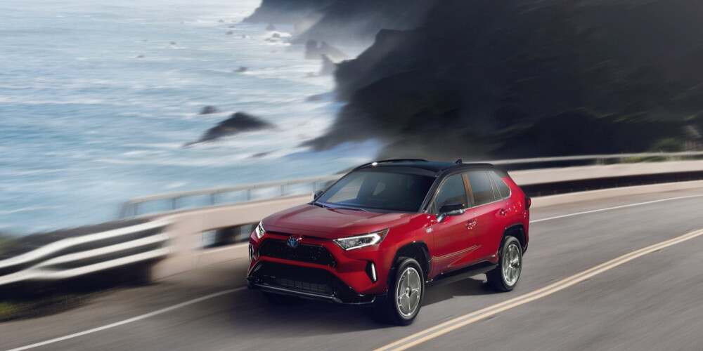 Red 2021 Toyota RAV4 Prime driving on coastline highway