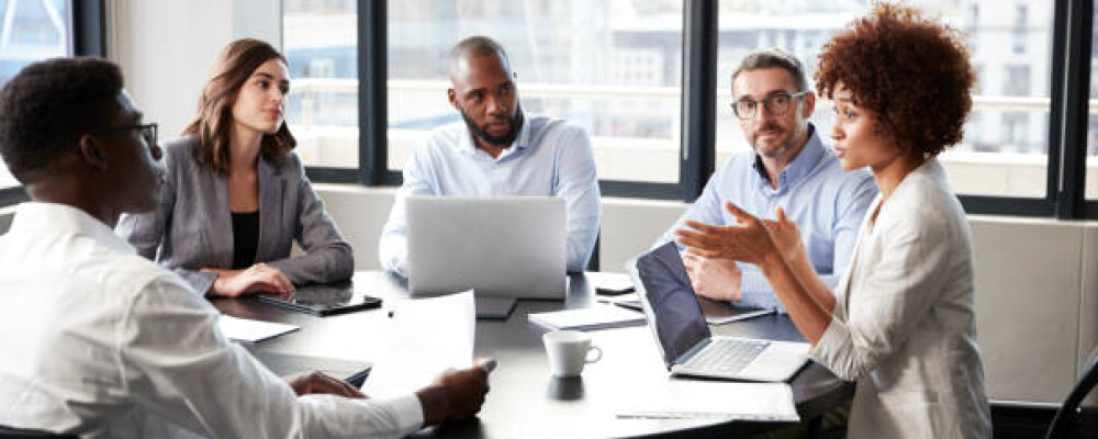 People Working Several people around a table on their computers talking