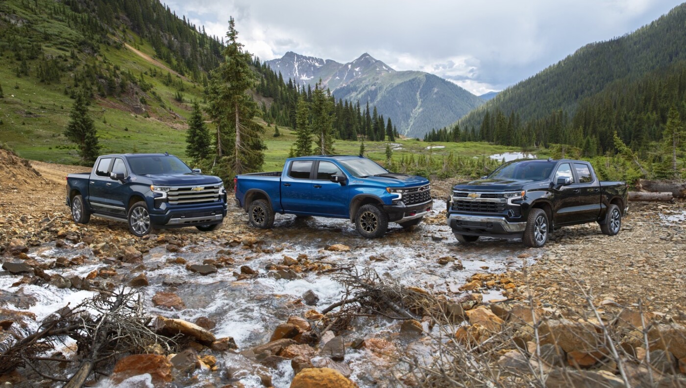 Three blue 2022 Chevy Silverado parked by mountain side