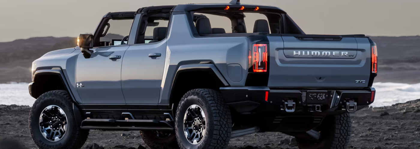 2025 GMC Hummer EV Truck The blue Hummer EV truck is parked on the beach near the ocean.