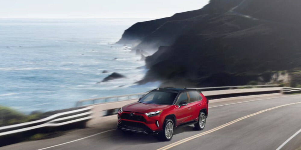 2026 Red Toyota RAV4 Hybrid driving on the coast 