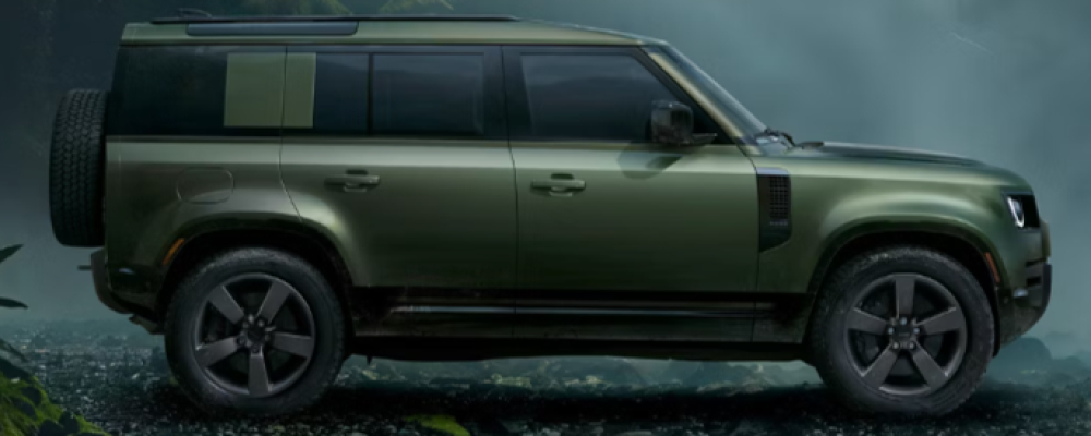 The green Defender 110 SUV is surrounded by fog.