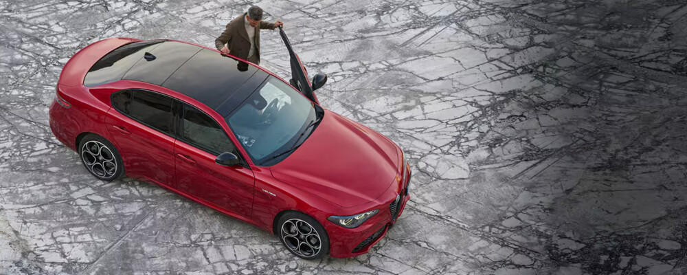 Person stands at drivers side of red Alfa Romeo Giulia
