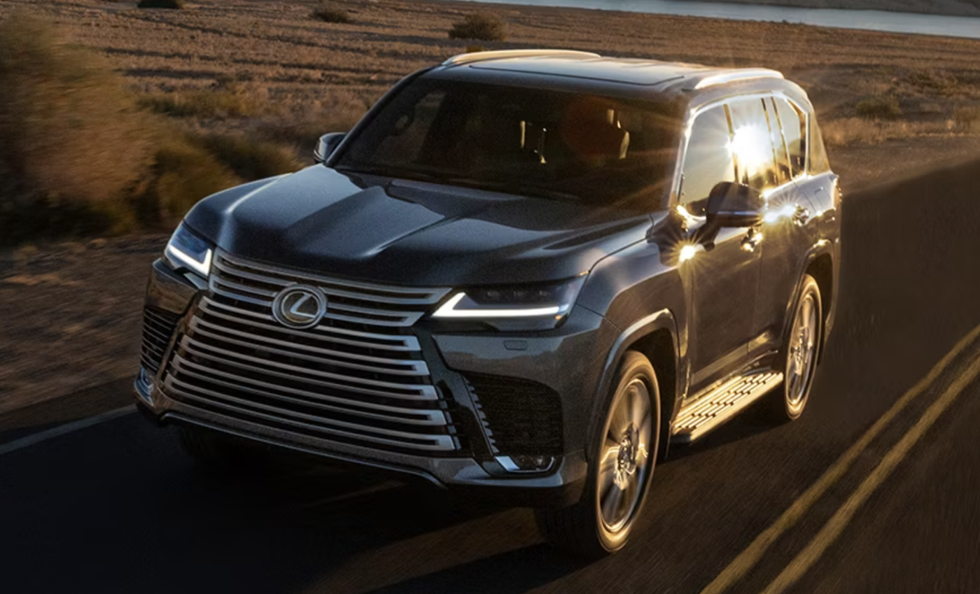 A black Lexus LX is driving down the road at sunset.