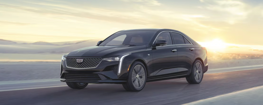 2025 Cadillac CT4 The black CT4 is driving along the ocean with the sunset behind it.