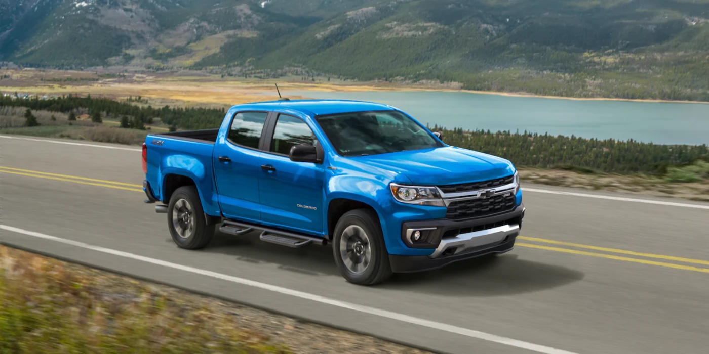 Blue Chevrolet Colorado driving on road near lake