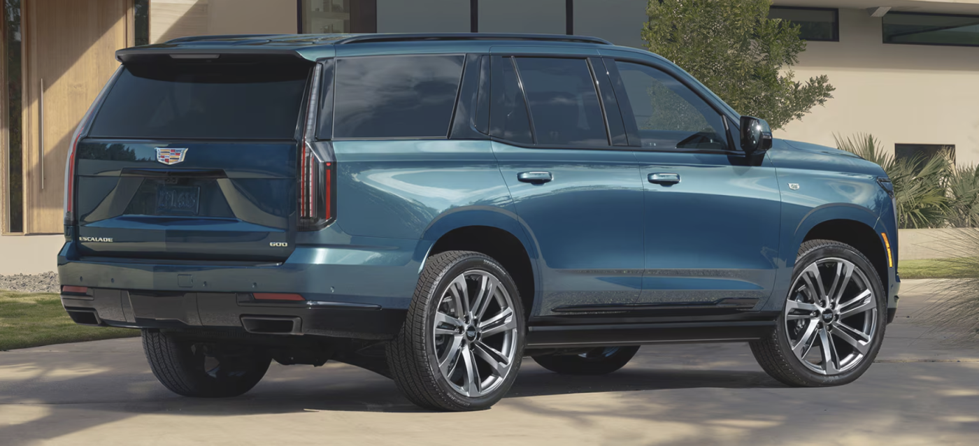 The metallic blue Escalade is parked in front of a house. 