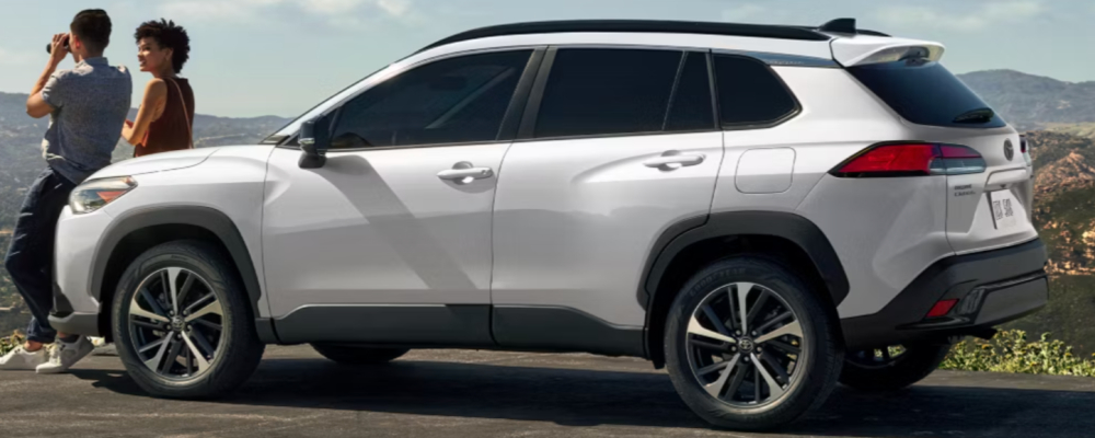 Two people are standing in front of a white SUV.