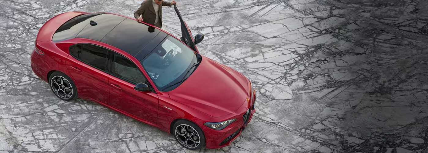2025 Alfa Romeo Giulia Person stands at drivers side of red Alfa Romeo Giulia