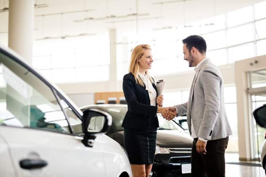 Woman shaking man's hand near vehicle 