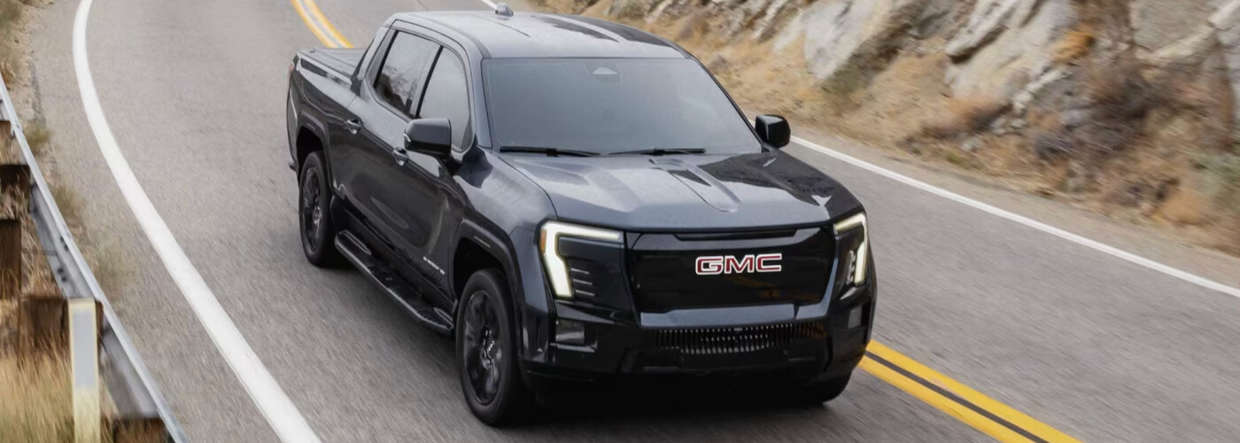 Black 2026 GMC Sierra EV driving on outdoor road
