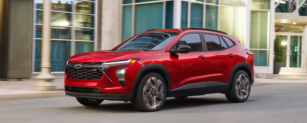Red Chevrolet Trax driving down city steet