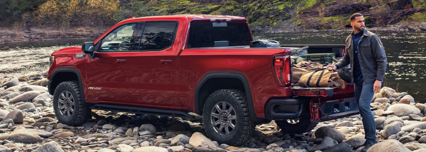 The red truck is parked on a riverbank. 